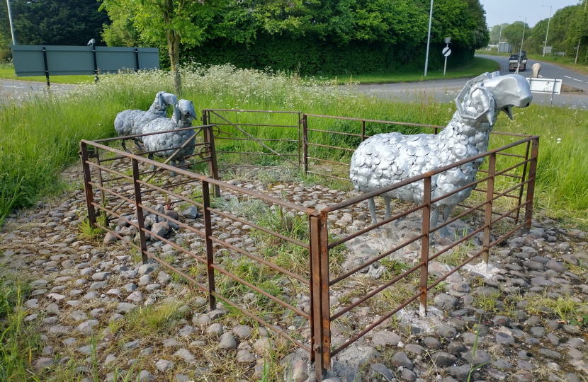 Yep metal sheep inside some metal railings with grass in the background