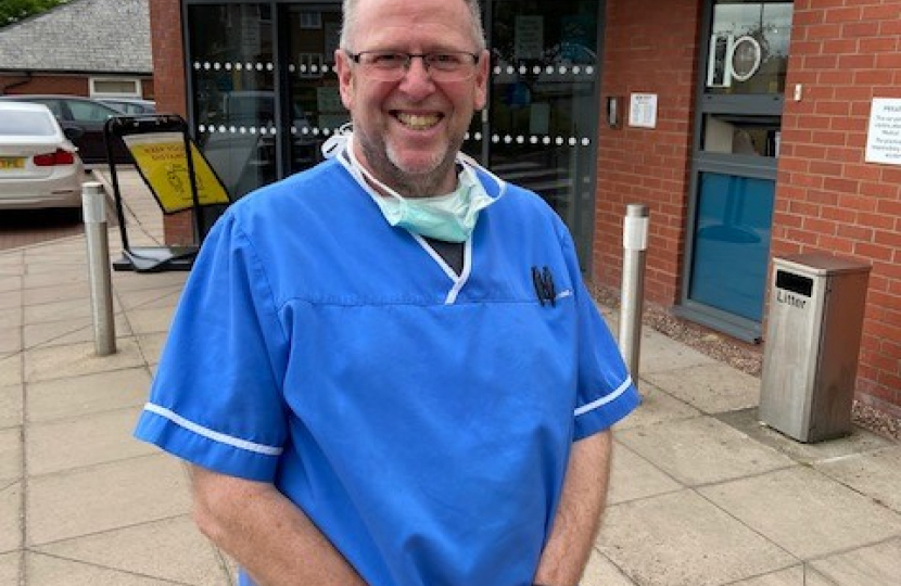 Cllr Nigel Dugmore standing in front of Donnington Pharmacy in his pharmacist uniform