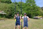 Cllr Tim Nelson with another rower holding an oar each. Both men are standing side by side on grass with trees and a blue sky behind them.