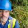 Cllr Tim Nelson wearing a blue hard hat standing in front of Himalayan Balsam