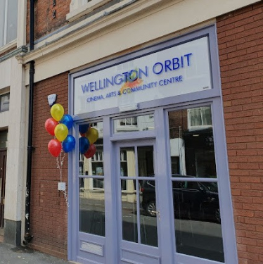 Frontage of the Orbit building. There are multi-coloured balloons to the left of the door.